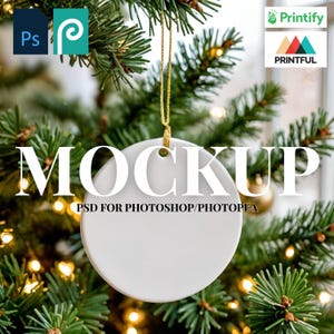 May include: White ceramic round ornament mockup hanging from a gold string, with the word "MOCKUP" in large white letters. The text "PSD FOR PHOTOSHOP/PHOTOPAE" is below the word "MOCKUP". The ornament is set against a backdrop of a Christmas tree.