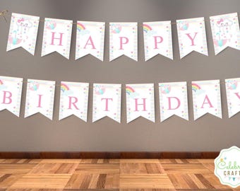 May include: A 'HAPPY BIRTHDAY' banner with pink lettering, featuring pastel rainbows, clouds, and umbrellas on each pennant. The banner is strung with twine, ideal for a birthday party or celebration.