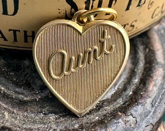 May include: Gold heart-shaped charm with the word "Aunt" engraved on it.