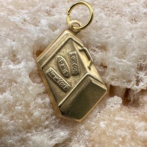 May include: Gold-toned charm shaped like a suitcase with the words "London", "Paris", and "New York" on it.
