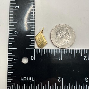 May include: A gold charm in the shape of a small box with the number "07" on the front. The charm is about the size of a US quarter.