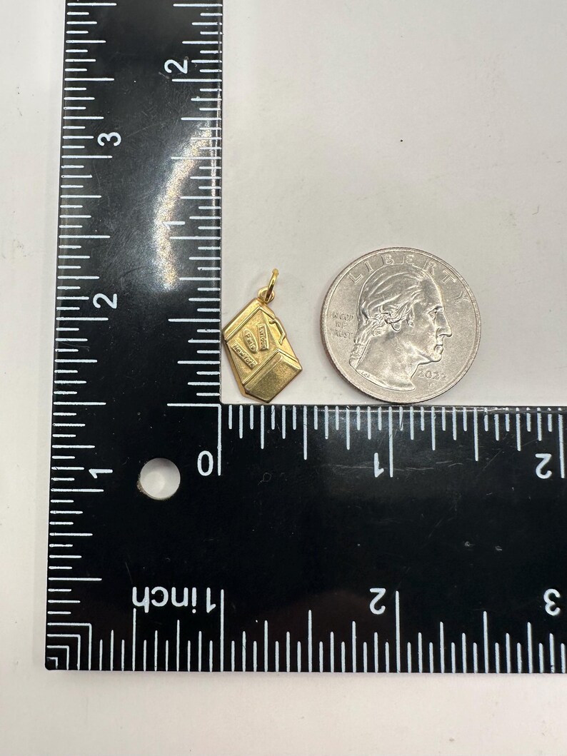 May include: A gold charm in the shape of a small box with the number "07" on the front. The charm is about the size of a US quarter.