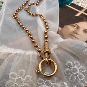 May include: A gold chain necklace with a round clasp. The chain is made of small, round links.