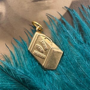 May include: Gold-toned luggage charm with the words "London", "Paris", and "New York" on it.