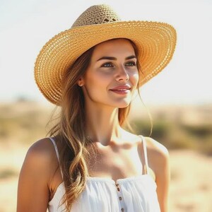 Puede incluir: Una mujer con un sombrero de paja de ala ancha y un vestido blanco. El sombrero tiene una copa redonda y un ala ancha, que proporciona sombra. El vestido es blanco con tirantes finos y una botonadura delantera. El fondo es una escena exterior borrosa.