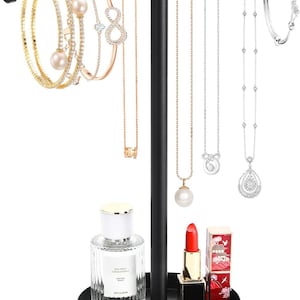 May include: A black metal jewelry organizer with a round base and a T-shaped top. The organizer holds various necklaces, bracelets, and rings. Also displayed are a perfume bottle, lipstick, and a small box.