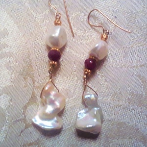 May include: A pair of gold earrings with white baroque pearls and burgundy red beads.