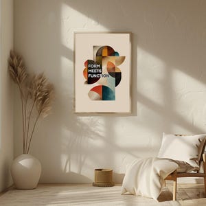 Può includere: Una stampa artistica incorniciata con il testo "FORM MEETS FUNCTION" presenta un design astratto di forme geometriche nei toni dell'arancione, del blu e del marrone. L'opera d'arte è appesa a una parete color crema, con un vaso di piante secche e una sedia di legno nelle vicinanze.