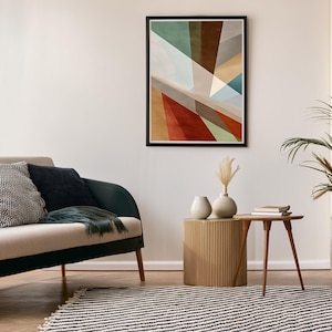 Op de afbeelding: Een moderne woonkamer met een beige bank, decoratieve kussens en een zwart-wit gestreept tapijt. Een ingelijst abstract kunstwerk hangt aan de muur, aangevuld met een kleine houten tafel en decoratieve vazen.
