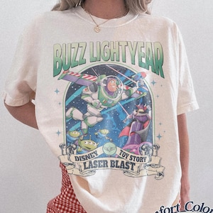 Puede incluir: Una taza de cerámica blanca con un asa negra y el texto "But First, Coffee" en negrita negra. La taza está sobre un fondo borroso. La taza mide aproximadamente 10 cm de altura.