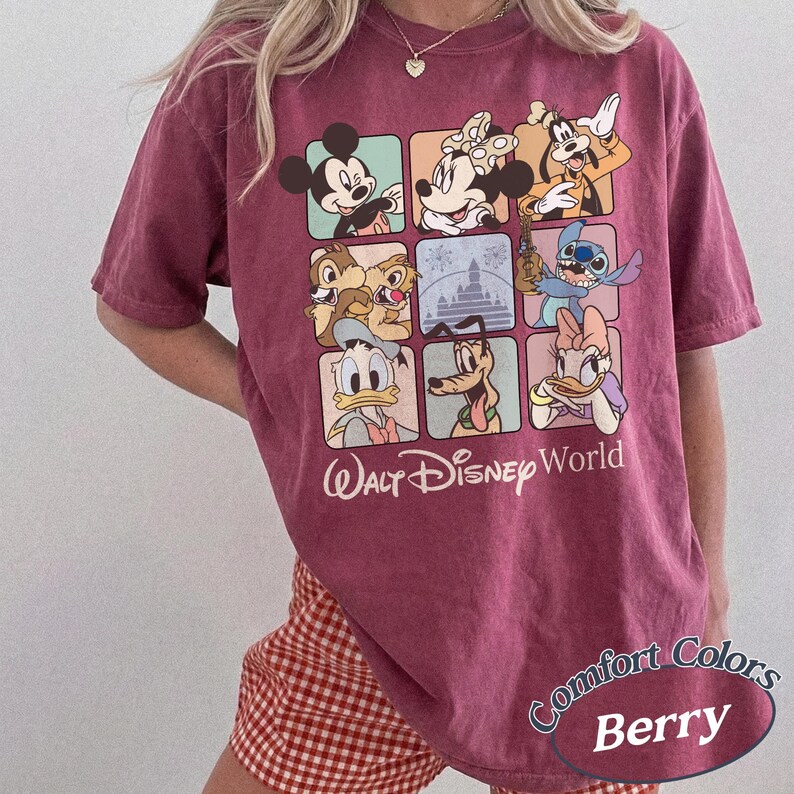 May include: Berry-colored t-shirt featuring a grid of Disney characters including Mickey Mouse, Minnie Mouse, and Goofy. The shirt has the words "Walt Disney World" printed below the grid. The shirt is a Comfort Colors brand.