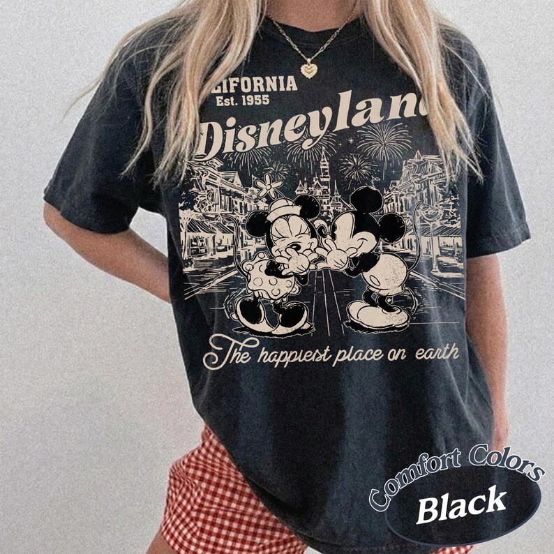 Puede incluir: Camiseta negra con un dise&ntilde;o vintage de Disneyland con Mickey y Minnie Mouse. El dise&ntilde;o incluye el texto "Disneyland" y "The happiest place on earth". La camiseta es de la marca Comfort Colors.