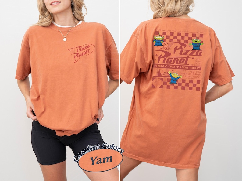 May include: Orange-colored t-shirt with the Pizza Planet logo on the front and back. The back of the shirt features the Pizza Planet logo, three green alien characters, and text that reads "Friday Night Kids Night".