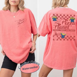 May include: A watermelon-colored t-shirt with the Pizza Planet logo on the front. The back of the shirt features the Pizza Planet logo, alien characters, and the text "Friday Night Kids Night".
