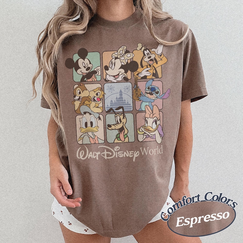 May include: Espresso-colored t-shirt featuring a grid of Disney characters including Mickey Mouse, Minnie Mouse, and Goofy. The shirt has the words "Walt Disney World" printed below the grid and "Comfort Colors Espresso" in an oval.