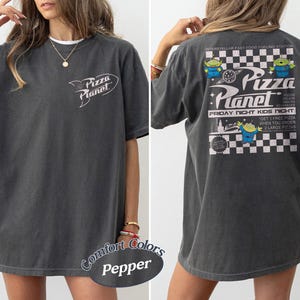 May include: Dark grey t-shirt with the "Pizza Planet" logo on the front and a graphic on the back. The back graphic features the text "Pizza Planet" with alien characters and the text "Friday Night Kids Night".