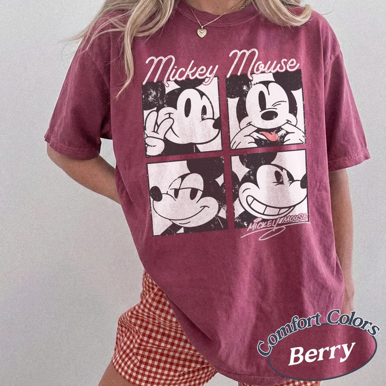 Op de afbeelding: Bessenkleurig T-shirt met een vierpaneels Mickey Mouse-afbeelding. Het ontwerp toont verschillende uitdrukkingen van Mickey Mouse. Het shirt heeft de woorden "Mickey Mouse" bovenaan en "Comfort Colors Berry" onderaan.