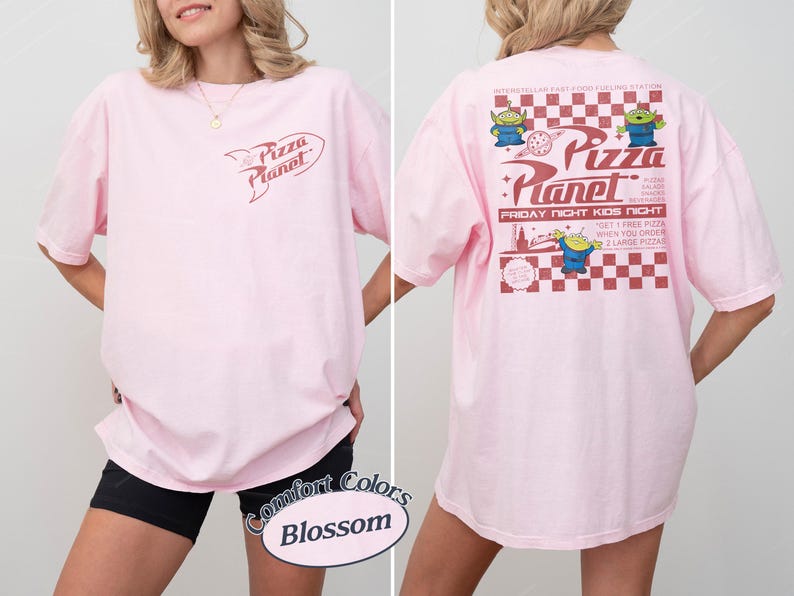 May include: Light pink t-shirt with the Pizza Planet logo on the front and back. The back features a red and white checkered design with cartoon aliens and text that reads "Pizza Planet" and "Friday Night Kids Night."
