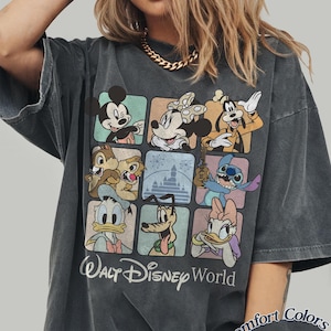 May include: Dark gray t-shirt featuring a grid of Disney characters including Mickey Mouse, Minnie Mouse, Goofy, Chip and Dale, Donald Duck, Pluto, Stitch, and Daisy Duck. The words "Walt Disney World" are printed below the grid. The shirt is labeled "Comfort Colors Pepper".