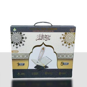 Op de afbeelding: Een rechthoekige doos met een handvat, met een kleurgecodeerde Tajweed Quran Read Pen. De doos heeft een zwart-goud ontwerp met Arabisch schrift en geometrische patronen. De voorkant toont een illustratie van de pen en een open boek.