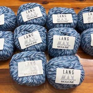 May include: A collection of ten blue and white yarn balls, each with a label that reads "LANG M.A.X. MOULINE." The yarn is arranged on a wooden surface. The yarn appears to be a blend of blue and white fibers.