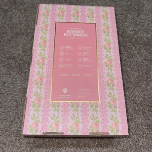 May include: A pink box with a floral pattern and the text "QUENCHER H2.0 TUMBLER". The box has a gold border and contains information about the product. The floral pattern includes pink roses and green leaves.