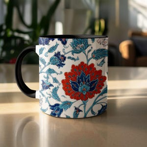 May include: A ceramic mug with a black handle and interior. The exterior features a floral design in red, blue, and turquoise against a white background. The design includes large flowers and intricate leaf patterns.