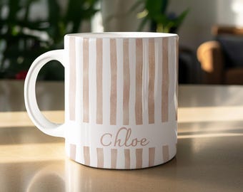 May include: White ceramic mug with vertical peach stripes and the name "Chloe" in a delicate script. The mug has a curved handle and is designed for hot beverages. The design is simple and elegant.