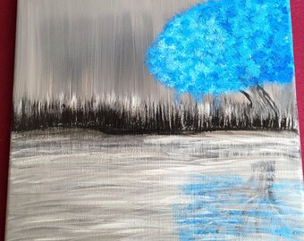 May include: A painting of a landscape featuring a vibrant blue tree against a gray sky. The tree's reflection is visible in the water below. The foreground shows a dark, textured area, possibly representing grass or a shoreline.