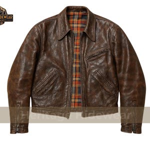 Puede incluir: Chaqueta de cuero marrón con cuello, bolsillos delanteros y forro a cuadros. La chaqueta tiene un aspecto desgastado y detalles de cremallera en las mangas. El logotipo de Heritage Hidewear está en la esquina superior izquierda.