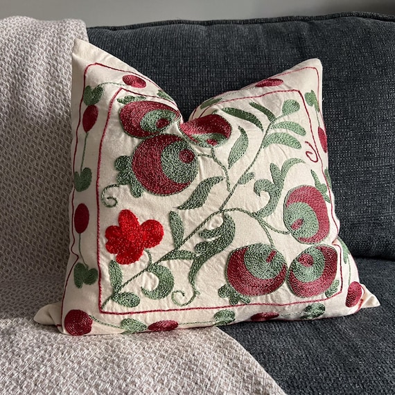Suzani pillow cover next to a kilim rug fragment, illustrating the difference between the two textile traditions