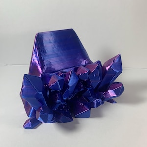 May include: An iridescent blue and purple crystal cluster, with a matching base. The crystals have sharp, geometric shapes and reflect light. This decorative piece is a striking example of modern design.