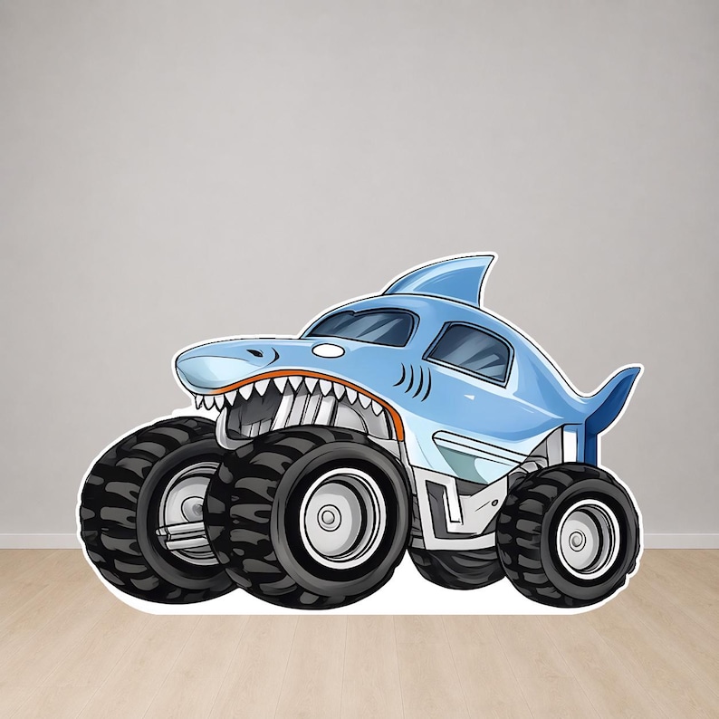 Op de afbeelding: Een lichtblauwe monstertruck met een haai-ontwerp. De truck heeft grote zwarte banden, een haaienvin en een grijnzende bek. De afbeelding is een cartoonillustratie.