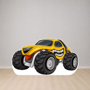 Op de afbeelding: Een gele cartoon monstertruck met grote zwarte banden en een grijnzend gezichtsontwerp. Het voertuig heeft een zilveren chassis en oranje accenten, waardoor het een speelse uitstraling heeft. Het ontwerp is gedurfd en opvallend.