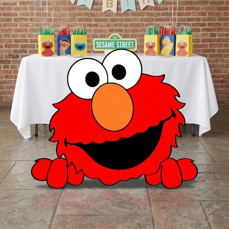 May include: A large, red Elmo cutout with a smiling face and outstretched arms is in the foreground. Behind it, a table is set with Sesame Street-themed party favors and a sign that reads "Sesame Street 123". A banner spells out "BIRTH".
