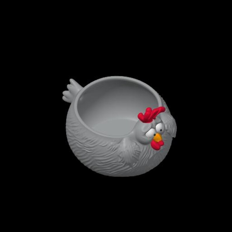May include: A gray, round, bowl-shaped container designed to resemble a chicken. The exterior features textured, feather-like details, while the front displays a red comb, a yellow beak, a red wattle, and two white eyes with black pupils.