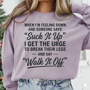 Puede incluir: Una sudadera lila con texto negro. El texto dice: "CUANDO ME SIENTO MAL Y ALGUIEN DICE 'Suck It Up' ME DAN GANAS DE ROMPERLES LAS PIERNAS Y DECIR 'Walk It Off'".