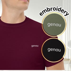 May include: Burgundy t-shirt with the word "genau" embroidered on the chest. The image also features two circular embroidery samples, one olive green and one black, each with the word "genau" in white.