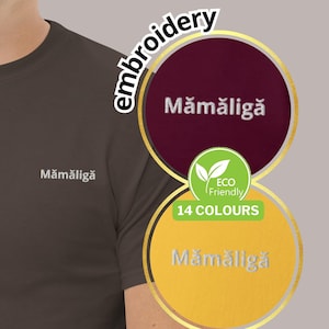 May include: A brown t-shirt with the word "Mămăligă" embroidered on the chest. The image also features a circular graphic with the same word, and the text "14 COLOURS" and "Eco Friendly".