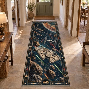 Op de afbeelding: Een lang rechthoekig loperkleed met een Star Wars ruimtegevechtscène met de Millennium Falcon, TIE-fighters en asteroïden tegen een donkerblauwe achtergrond. Het kleed heeft een decoratieve rand met symbolen en het Star Wars-logo.