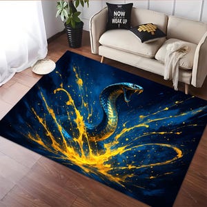 Op de afbeelding: Rechthoekig vloerkleed met een gestileerd cobra-ontwerp, open mond, tegen een donkerblauwe achtergrond met gele verfspatten. Een decoratief item voor in huis, ideaal voor een woon- of slaapkamer.