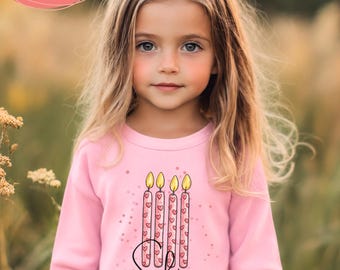 May include: A light pink long-sleeve sweatshirt featuring a graphic of four lit candles decorated with small red hearts. The name Sophia is printed in black cursive script below the candles. The sweatshirt has a crew neckline and long sleeves.