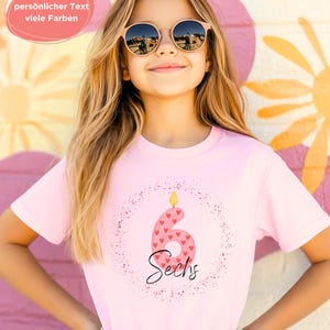 K&ouml;nnte beinhalten: Ein rosa T-Shirt mit der Zahl 6, verziert mit Herzen und dem Wort "Sechs". Das Shirt hat ein Geburtstagsthema, mit einer Kerzenflamme auf der Zahl. Der Text "pers&ouml;nlicher Text viele Farben" befindet sich in einem rosa Oval.
