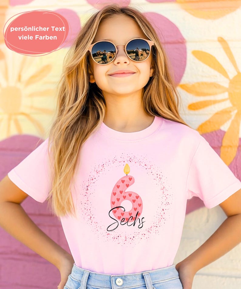 K&ouml;nnte beinhalten: Ein rosa T-Shirt mit der Zahl 6, verziert mit Herzen und dem Wort "Sechs". Das Shirt hat ein Geburtstagsthema, mit einer Kerzenflamme auf der Zahl. Der Text "pers&ouml;nlicher Text viele Farben" befindet sich in einem rosa Oval.