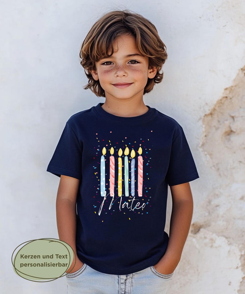 May include: A navy blue t-shirt featuring a colorful birthday candle design with the name "Mateo" in white script. The shirt has a confetti pattern and is worn by a young person.