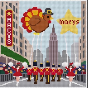 May include: A cross-stitch pattern depicting a city parade scene with a brown turkey balloon wearing a pilgrim hat, a yellow star balloon labeled macys, and a vertical sign reading MACYS. Marching band members in red uniforms and dancers are shown.