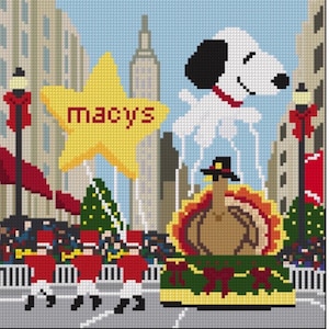May include: A cross-stitch pattern depicting a parade scene with a large yellow star featuring the text macys, a white dog balloon, a turkey float, and marching band members in red uniforms against a backdrop of city skyscrapers.