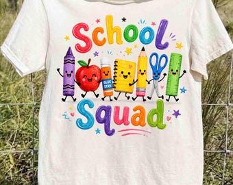 May include: A cream-colored t-shirt featuring a colorful graphic with the text School Squad. The design includes cartoon-style school supplies: a purple crayon, a red apple, a glue stick, a yellow notebook, a pencil, blue scissors, and a green ruler.