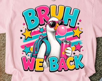 May include: A light pink t-shirt featuring a graphic of a white goose wearing pink sunglasses and a teal backpack. The goose is blowing a pink bubble and holding a pink tumbler. The text reads BRUH WE BACK in colorful, bold, block letters.