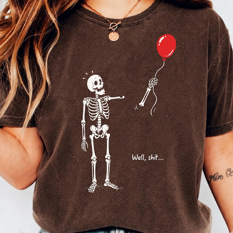 Brown shirt mockup featuring Skeleton Lost Balloon, Well Shit skeleton quote and funny gothic Halloween shirt design.